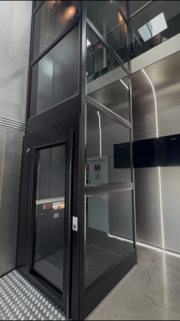 Black platform lift with glass shaft installed by Direct Lift Solutions